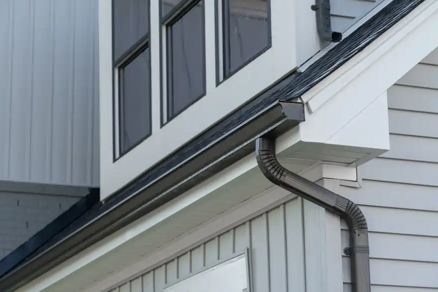Black seamless gutter and downspout on white board-and-batten siding