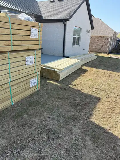Treated lumber delivered beside a ground-level deck frame