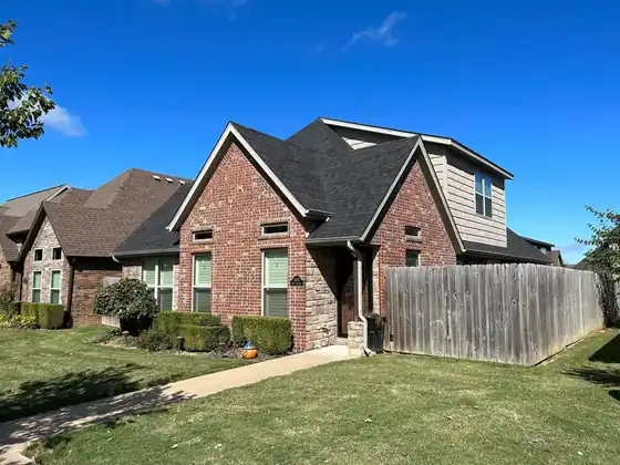Brick house with a finished roof and a wood privacy fence
