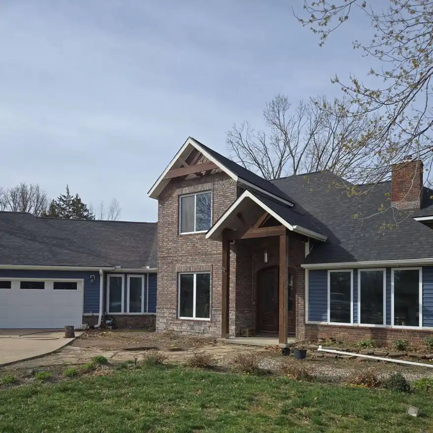 A brick and blue-sided home after an Elite Home Solutions exterior remodel and new roof