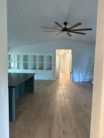 Open-plan room after a remodel with a ceiling fan and built-ins