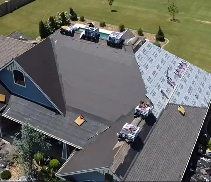 Aerial view of an Elite Home Solutions reroof in progress with shingle bundles staged on the roof