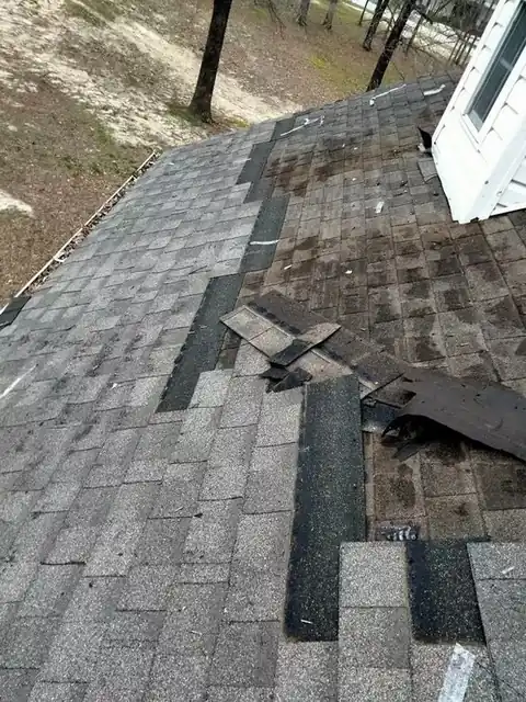Storm-torn shingles on a roof slope