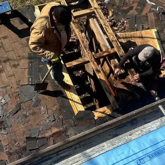 Two Elite Home Solutions roofers rebuilding chimney framing from above
